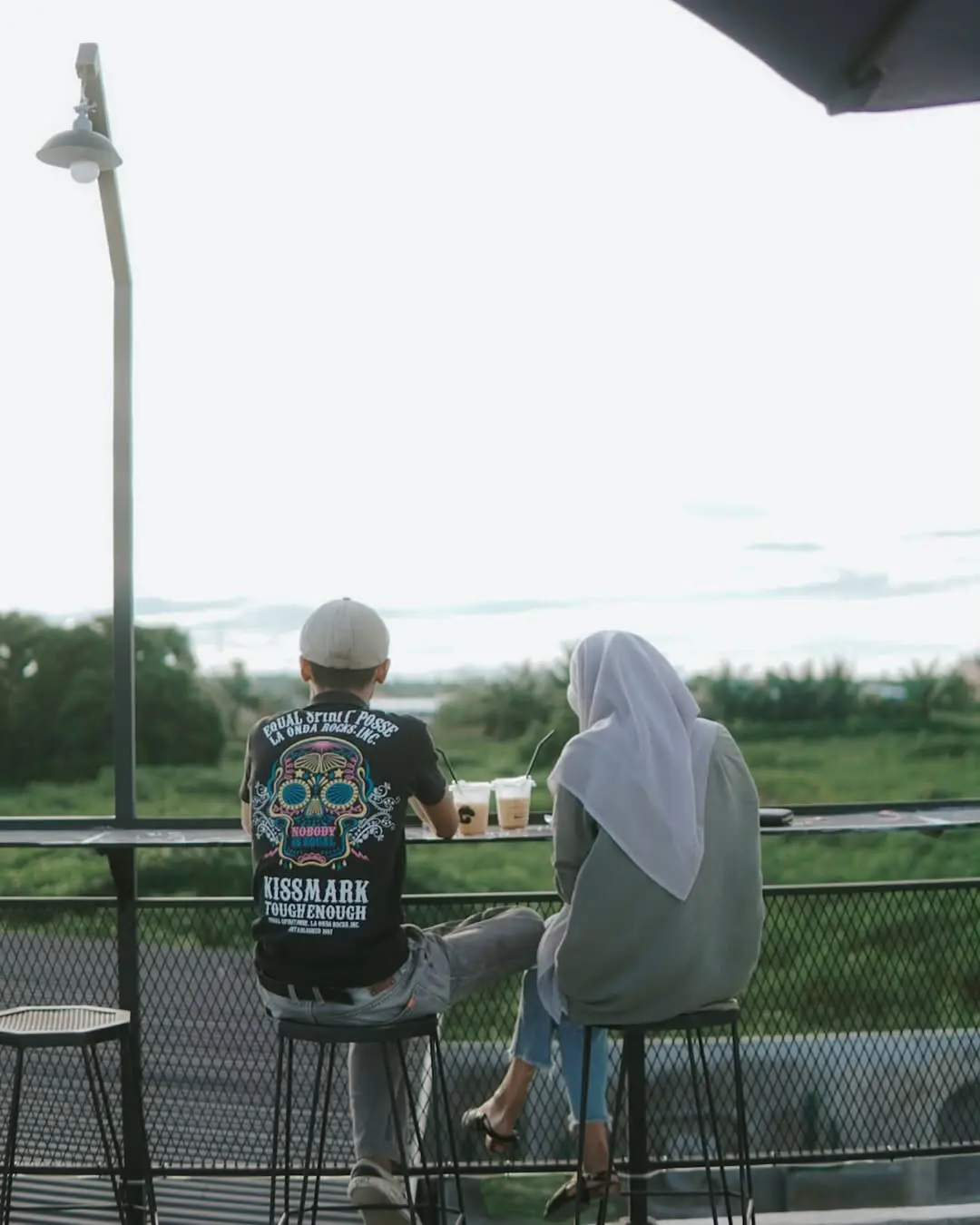 Pengunjung bersantai di area outdoor Lokaria Coffee Perdagangan dengan latar hijau